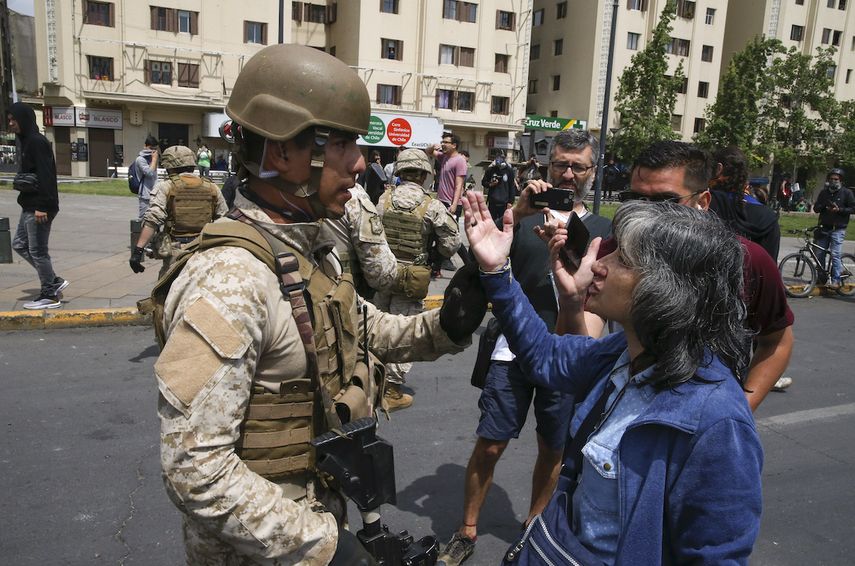Un soldado discute con una mujer en la calle despu&eacute;s que una noche de disturbios oblig&oacute; al presidente Sebasti&aacute;n Pi&ntilde;era a declarar el estado de emergencia en Santiago, Chile, s&aacute;bado 19 de octubre de 2019.&nbsp;