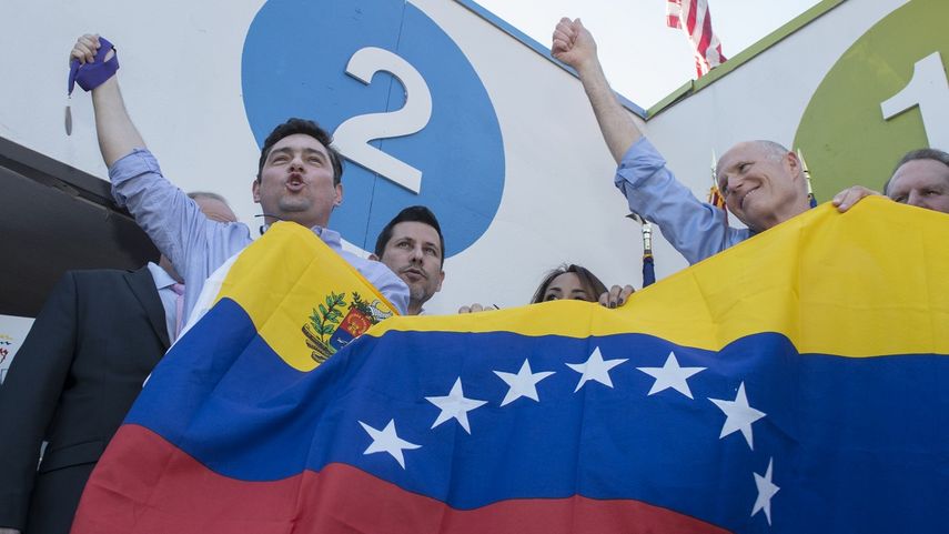El gobernador de Florida, Rick Scott (der.) sostiene una bandera de Venezuela junto al coordinador del partido Voluntad Popular en Miami, Carlos Vecchio (izq.).