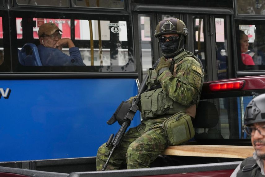 Un soldado se sienta en la parte trasera de un camión mientras patrulla frente a un autobús de cercanías en el norte de Quito, Ecuador.