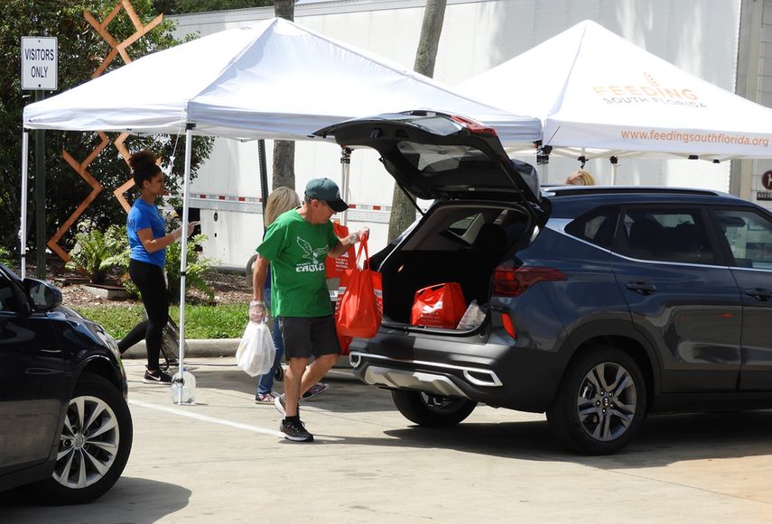 Un voluntario deposita bolsas con alimentos en el ba&uacute;l de un autom&oacute;vil.