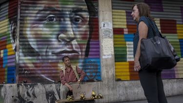 Un vendedor callejero ofrece bananas frente a una pintura con la imagen del líder independentista venezolano Simón Bolívar en Caracas, Venezuela, el martes 16 de julio de 2019.