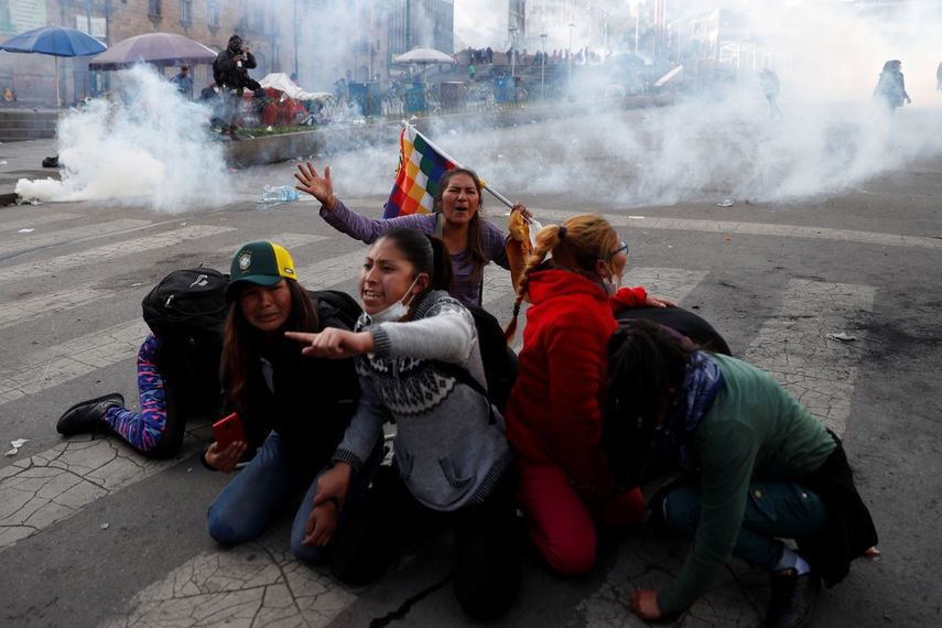 Manifestantes a favor del expresidente boliviano Evo Morales se protegen de las nubes de gas lacrim&oacute;geno lanzado por la polic&iacute;a, en La Paz, Bolivia, el 15 de noviembre de 2019.&nbsp;