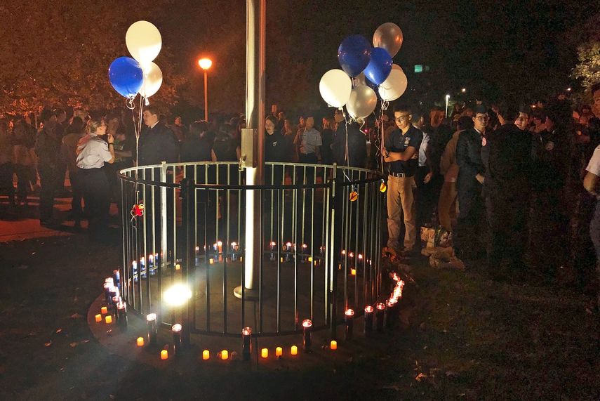 Varias personas se re&uacute;nen alrededor de un asta adornada con velas y globos de colores azul, dorado y blanco, representativos de la Escuela Secundaria Saugus, en el Parque Central de Santa Clarita, California, despu&eacute;s de un tiroteo en la escuela, el jueves 14 de noviembre de 2019.&nbsp;