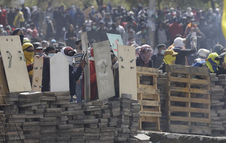 Manifestantes contrarios al gobierno se cubren tras una barricada en choques con la polic&iacute;a en Quito, Ecuador el 12 de octubre de 2019.