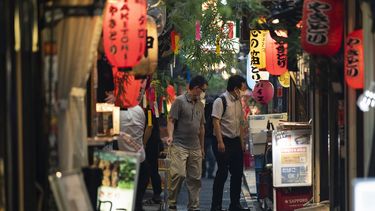 Dos hombres se detienen a mirar un restaurante en Tokio, el 9 de julio de 2021.&nbsp; 