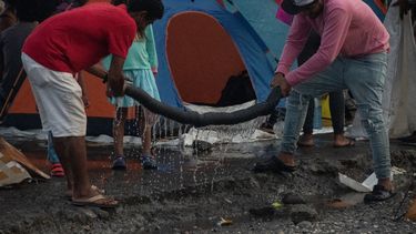 Migrantes estrujan una toalla en un refugio improvisado en Paso Canoas, a unos 300 km al sur de San José, en la provincia de Puntarenas, Costa Rica, el 26 de septiembre de 2023.&nbsp;