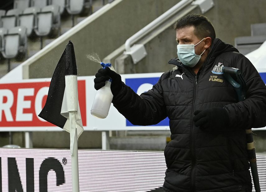 Un empleado rocía desinfectante la bandera de córner previo al partido de la Liga Premier inglesa entre Newcastle y Leicester City en el estadio St. James Park en Newcastle, el domingo 3 de enero de 2021.