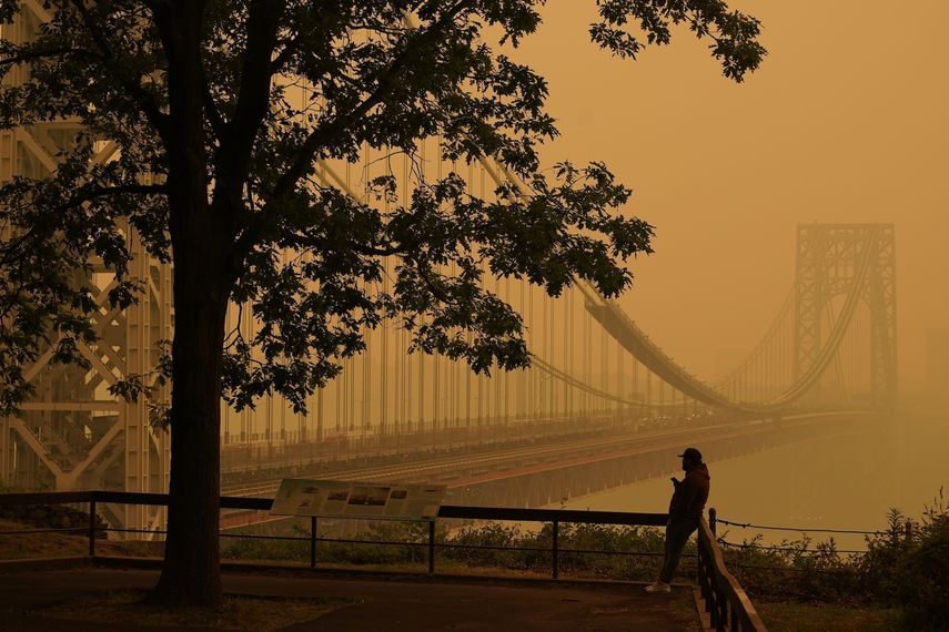 Un hombre habla por teléfono mientras la neblina cubre el puente George Washington en Fort Lee, Nueva Jersey, el 7 de junio de 2023. El verano ha venido acompañado de humo y los científicos dicen que probablemente será peor en los próximos años debido al calentamiento global.