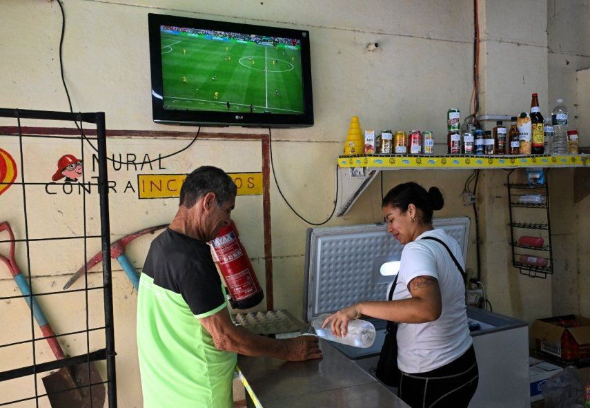 En la imagen se observa a un hombre y una mujer en La Habana, Cuba, junto a una televisión con transmisión del juego inaugural del Mundial de Norteamérica entre México y Sudáfrica, el 11 de junio de 2026.