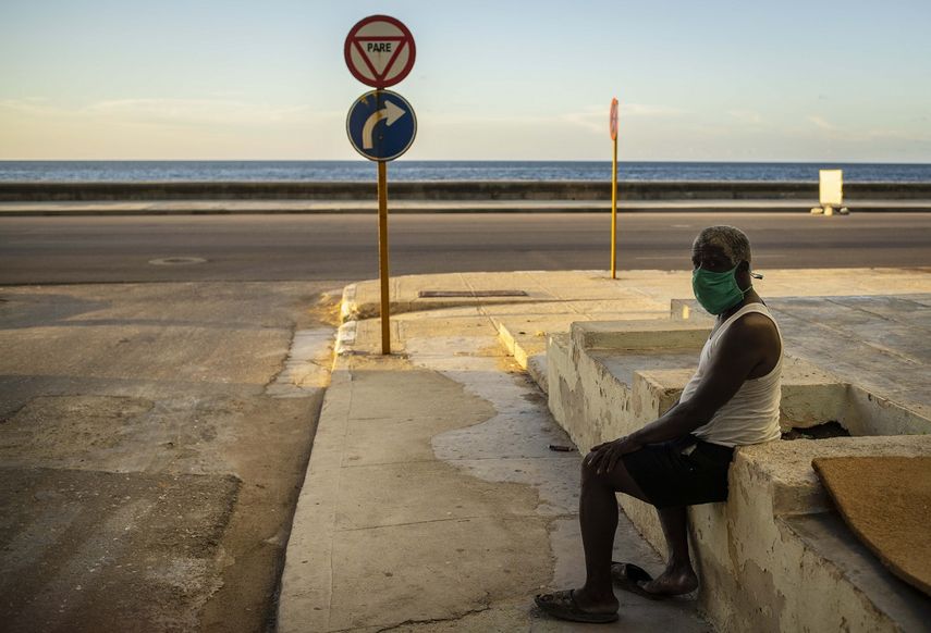 Un hombre que usa una máscara como precaución contra la propagación del nuevo coronavirus descansa en el malecón del malecón en La Habana, Cuba, el lunes 31 de agosto de 2020.