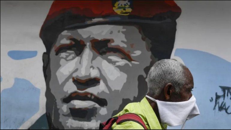 NOTICIA DE VENEZUELA  - Página 9 Un-hombre-que-porta-una-mascarilla-improvisada-protegerse-del-coronavirus-camina-el-domingo-29-marzo-2020-junto-un-mural-del-fallecido-hugo-chavez-caracas-venezuela