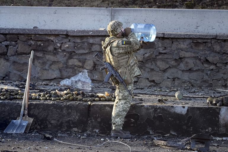 Un soldado ucraniano toma agua junto a granadas y restos de camiones militares calcinados, en una calle de Kiev, Ucrania, el 26 de febrero de 2022. 