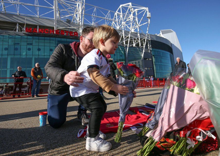 Un niño coloca flores en memoria a Bobby Charlton a los pies de la estatua The United Trinity en las afueras de Old Trafford, estadio del Manchester United el domingo 22 de octubre del 2023.&nbsp;
