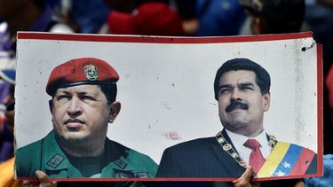 Partidario del Régimen sostiene folleto con los retratos de Hugo Chávez y Nicolás Maduro, mientras participa durante una marcha en Venezuela