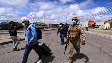 Un soldado chileno escolta a migrantes a las instalaciones policiales en Colchane, Chile, en la frontera con Bolivia. La frontera chilena está cerrada después de que el sábado entrara en vigor una nueva ley de migración. Esa ley ordena a policías y militares redireccionar a la frontera a cualquier extranjero que evada el control migratorio.