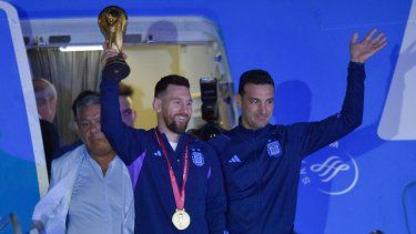 El futbolista argentino Lionel Messi sostiene el trofeo del Mundial de la FIFA a la salida de un avión junto al técnico Lionel Scaloni, en Buenos Aires, Argentina, el martes 20 de diciembre 2022.&nbsp;