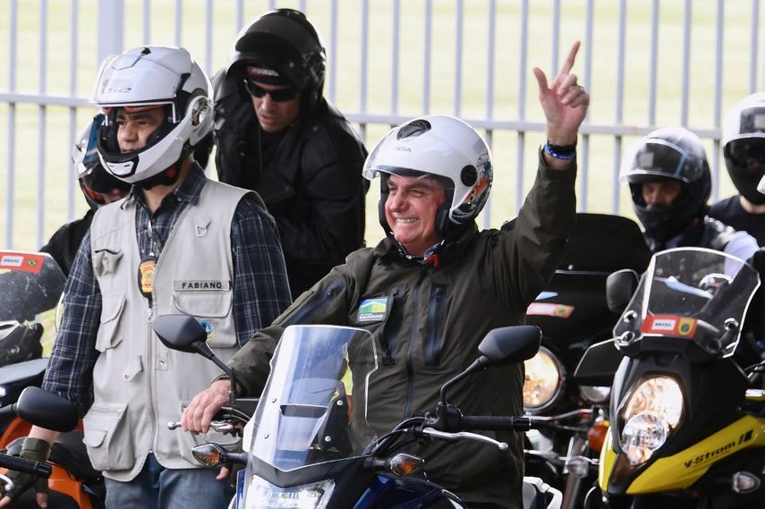 El presidente de Brasil, Jair Bolsonaro, saluda a sus partidarios mientras conduce una motocicleta al frente de una caravana de más de 1000 ciclistas para celebrar el Día de la Madre en Brasilia el 9 de mayo de 2021.