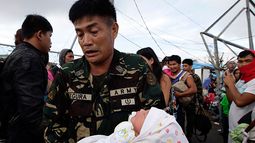 Un soldado traslada a Ian Daniel Honrado, de un día de nacido, a un avión militar en el aeropuerto de Tacloban, Filipinas. (Foto AP/Bullit Marquez)