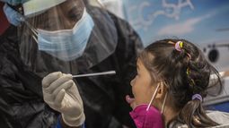 Una empleada de salud toma una muestra para una prueba de COVID-19 a una niña que acaba de llegar desde Cancún, México, en el Aeropuerto Internacional José Martí de La Habana