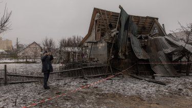 Un hombre toma fotografías con su teléfono móvil junto a una casa destruida tras un bombardeo ruso en Kiev, el 11 de diciembre de 2023, en medio de la invasión rusa de Ucrania.