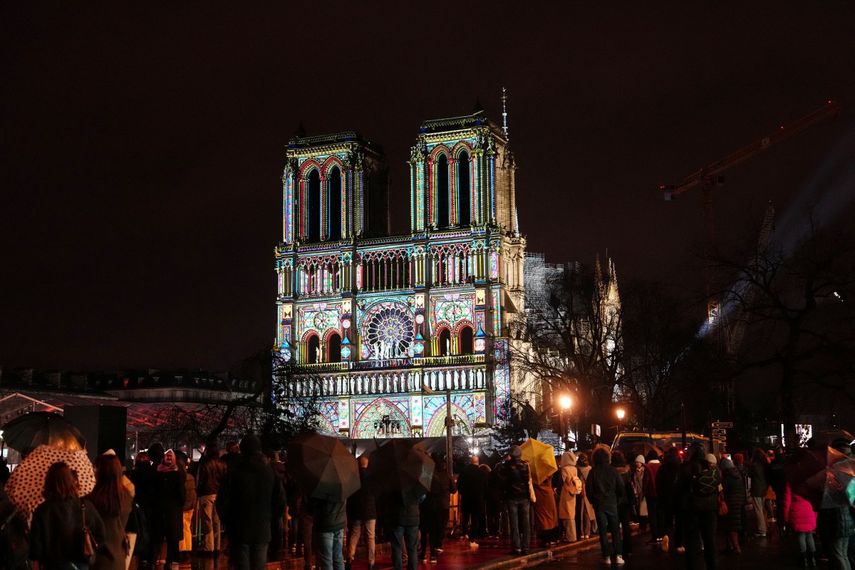 Una multitud se reúne en el exterior de la catedral de Notre Dame mientras se ilumina durante una ceremonia para conmemorar la reapertura de la emblemática catedral, en el centro de París, el 7 de diciembre de 2024. &nbsp; &nbsp;