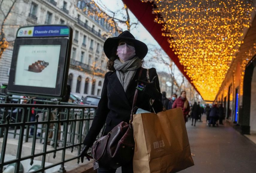 Una mujer con mascarilla para protegerse del COVID-19 camina con una bolsa de compras en un centro comercial, el viernes 17 de diciembre de 2021, en París.&nbsp;