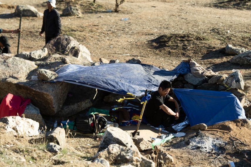 Un migrante chino se sienta frente a su tienda de campaña en un campamento para migrantes del lado estadounidense del muro fronterizo que separa a México de Estados Unidos en Jacumba, California, el 6 de diciembre de 2023.