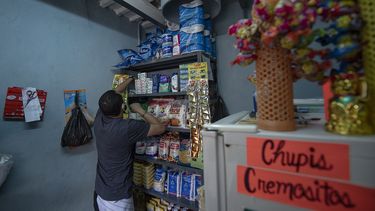Rosmer Díaz, un empleado público cuyo trabajo está paralizado por la cuarentena por el COVID-19, arregla mercadería dentro de una pequeña tienda que instaló en lo que solía ser el área de basura de un edificio de viviendas públicas en el barrio San Agustín de Caracas, Venezuela, el domingo 23 de agosto de 2020.