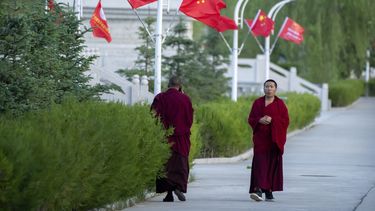 Dos monejes tibetanos caminan por una avenida.