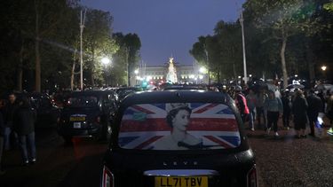 Un taxi que muestra una fotografía de la reina atraviesa multitudes de simpatizantes en The Mall mientras la gente se reúne fuera del Palacio de Buckingham, después del anuncio de la muerte de Isabel II, en el centro de Londres el 8 de septiembre de 2022.&nbsp;