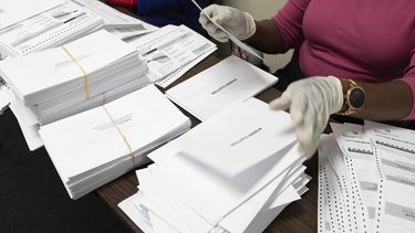 Trabajadores electorales preparan boletas de voto por correo.