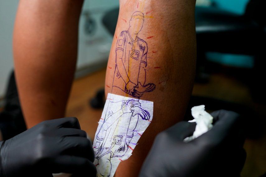 El artista Mariano Finkelstein trabaja en un tatuaje del arquero argentino Emiliano Martínez haciendo un gesto con su trofeo de guante de oro durante la ceremonia de premiación de la Copa del Mundo en Qatar 2022, en el cliente Valentin Bobadilla en Buenos Aires, Argentina, el jueves 29 de diciembre de 2022. 