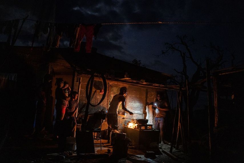 La familia Ramos prepara la cena en el fuego afuera de su casa dañada por el huracán Ian mientras continúa sin electricidad una semana después del paso del ciclón en La Coloma, provincia de Pinar del Río, Cuba, el miércoles 5 de octubre de 2022. 