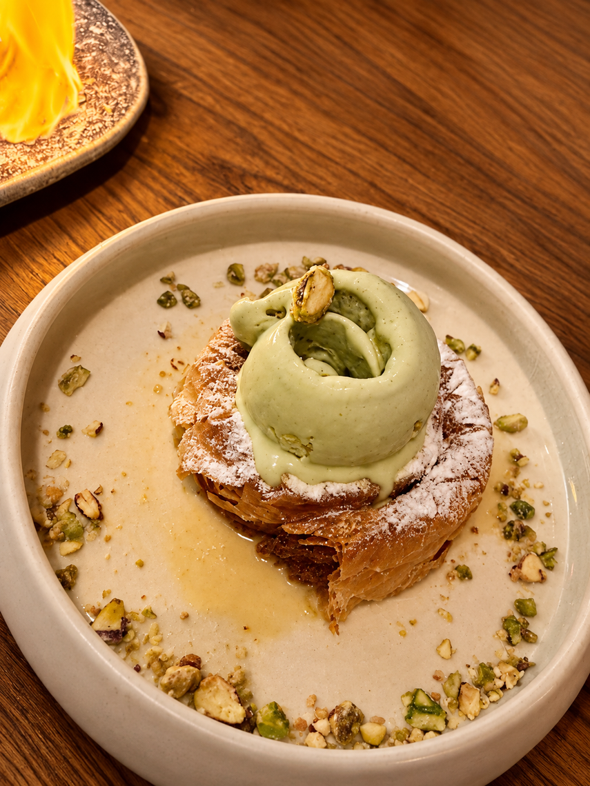 Un dulce de hojaldre se sirve con helado y trocitos de pistacho.