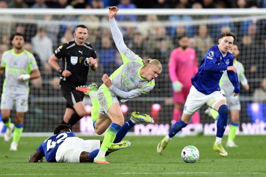 El delantero noruego del Manchester City, Erling Haaland (C), número 9, es placado por el centrocampista inglés del Everton, Tim Iroegbunam (I), número 42, durante el partido de la Premier League entre el Everton y el Manchester City en el estadio Hill Dickinson de Liverpool el 4 de mayo de 2026.&nbsp;