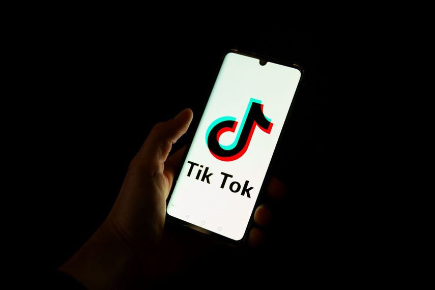 Esta fotografía tomada el 19 de abril de 2024 muestra a un hombre sosteniendo un teléfono inteligente que muestra el logotipo de la plataforma de redes sociales china Tiktok en una oficina en París.