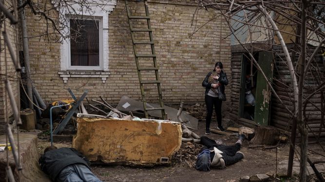 Ira Gavriluk carga a su gato mientras camina cerca de los cadáveres de su esposo, su hermano y otro hombre, que fueron asesinados en el exterior de su casa en Bucha, en las afueras de Kiev, Ucrania, el lunes 4 de abril de 2022.