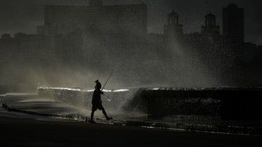 Una persona pesca a lo largo del malecón mientras las olas rompen durante un corte de energía en La Habana, Cuba, el lunes 21 de octubre de 2024.&nbsp;