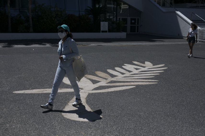 Una mujer con una m&aacute;scara para protegerse del coronavirus camina sobre un dibujo de la Palma de Oro frente al Palais des Festivals en Cannes, Francia, el martes 12 de mayo de 2020.&nbsp;