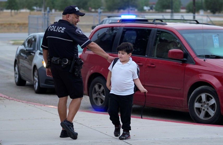 El agente Ruben Cardenas, del Distrito Escolar Independiente del Sur, a la izquierda, saluda a un chico que llega a la Escuela Primaria Freedom, el miércoles 23 de agosto de 2023, en San Antonio, Texas.&nbsp;
