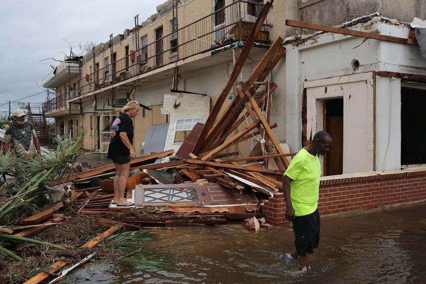 Una pareja de habitantes intenta llegar a su residencia que quedó inundada tras el paso del huracán Michael.&nbsp;