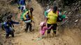 &nbsp;Una mujer trata de levantar a una niña de un paso enlodado mientras migrantes ecuatorianos atraviesan la selva del Darién para llegar desde Colombia a Panamá en su ruta hacia Estados Unidos, el 15 de octubre de 2022