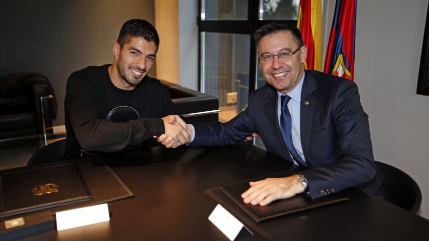 Luis Suárez (izquierda) estrecha la mano del presidente del Barcelona, Josep María Bartomeu (derecha) tras firmar la renovación de su contrato con la entidad azulgrana