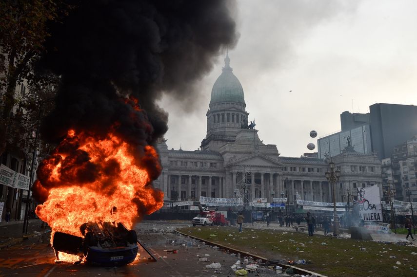 Un automóvil arde durante enfrentamientos entre la policía y manifestantes antigubernamentales frente al Congreso, donde los senadores debaten proyectos de ley promovidos por el presidente argentino Javier Milei en Buenos Aires, Argentina, el miércoles 12 de junio de 2024