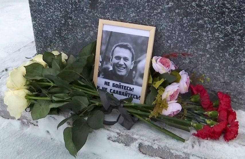 En esta imagen tomada de un video, se muestran las flores y una foto del líder opositor ruso Alexei Navalny depositados por su madre, Lyudmila Navalnaya, en su memoria en un monumento a las víctimas de la represión política, en Salekhard, a 1937 kms (1211 millas) al noreste de Moscú, Rusia, el 20 de febrero de 2024.