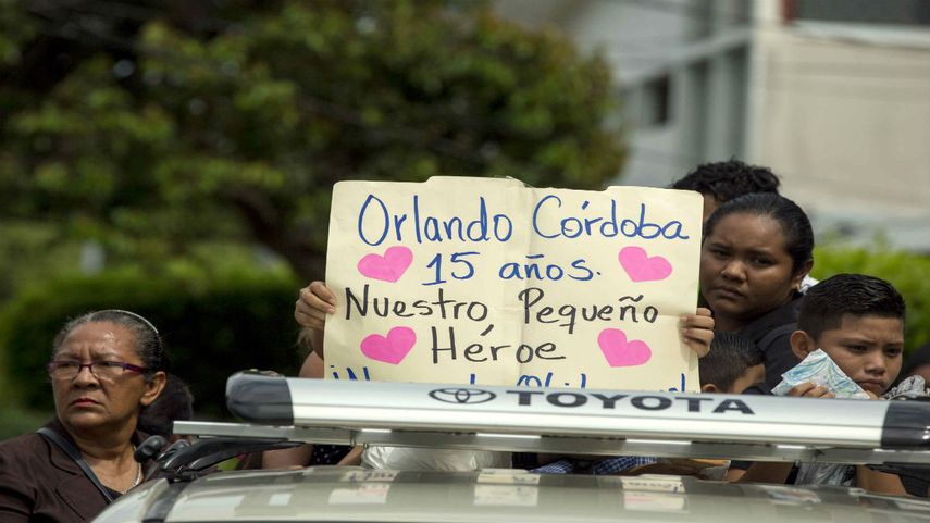 Familiares de un joven de 15 años que fue asesinado en la madre de todas las marchas llevan un cartel durante su entierro