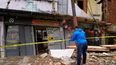 Un trabajador del ayuntamiento coloca una cinta de precaución afuera de una casa que se derrumbó parcialmente el día anterior durante las fuertes lluvias en el barrio de Catia en Caracas, Venezuela. Unas 10 casas en el área se derrumbaron.