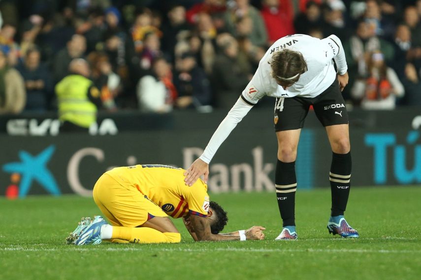 Yarek Gasiorowski, del Valencia, trata de consolar al brasileño Raphinha, del Barcelona, tras el empate en un partido de La Liga, el sábado 16 de diciembre de 2023.