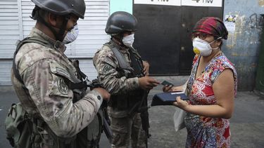 Una mujer explica a los soldados que est&aacute; buscando alcohol en farmacias, antes de que la dejen continuar su camino, en el tercer d&iacute;a del estado de emergencia en Lima, Per&uacute;, el mi&eacute;rcoles 18 de marzo de 2020.