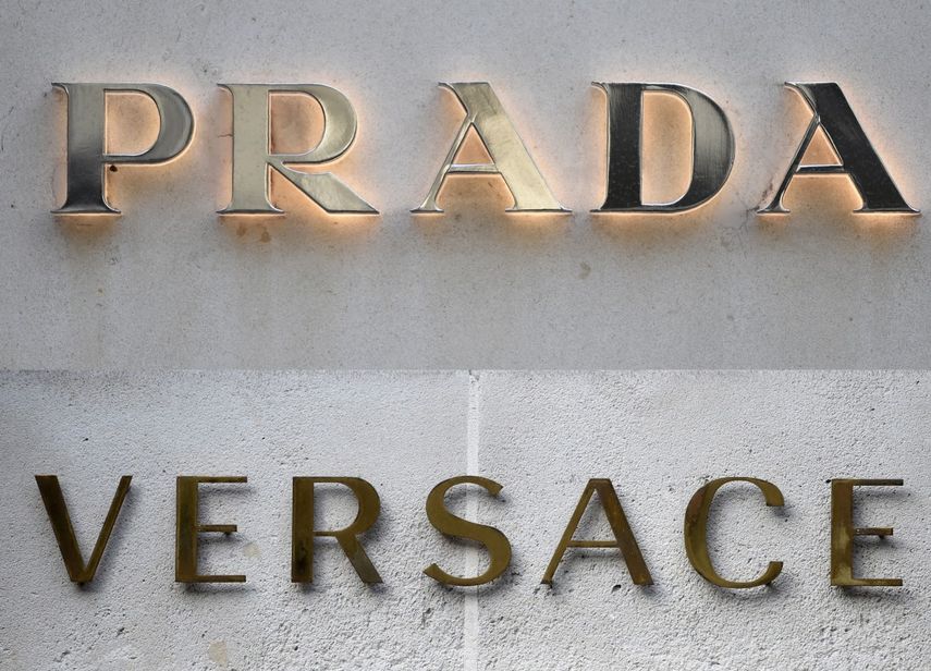 Esta combinación de imágenes, creada el 10 de abril de 2025, muestra una imagen de archivo del logotipo de la tienda de Versace, y del logotipo en el exterior de la tienda de la casa de moda y artículos de lujo Prada en París. &nbsp;
